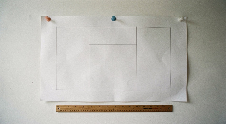 Un bureau en fin de journée, écran d’ordinateur allumé sur un document de projet, carnet ouvert et téléphone posé à côté, lumière chaude d’une lampe de bureau, cadrage serré sur le plan de travail.